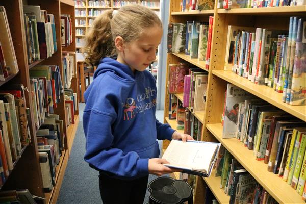 student looking through a book in the library